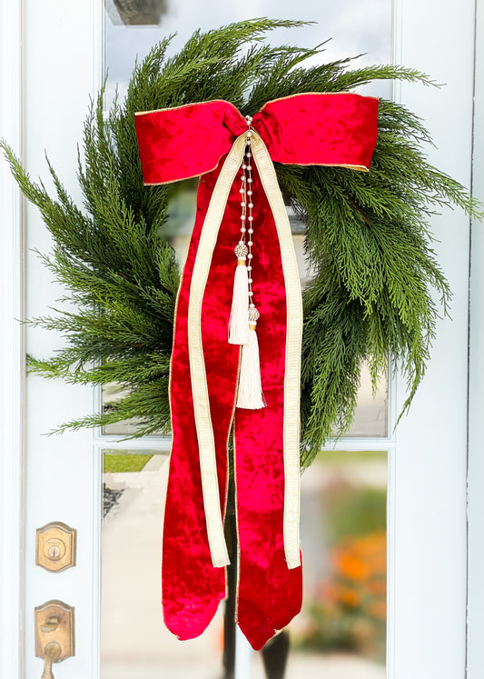 The Red Noel Cedar Wreath And Bow With Pearl Tassel.